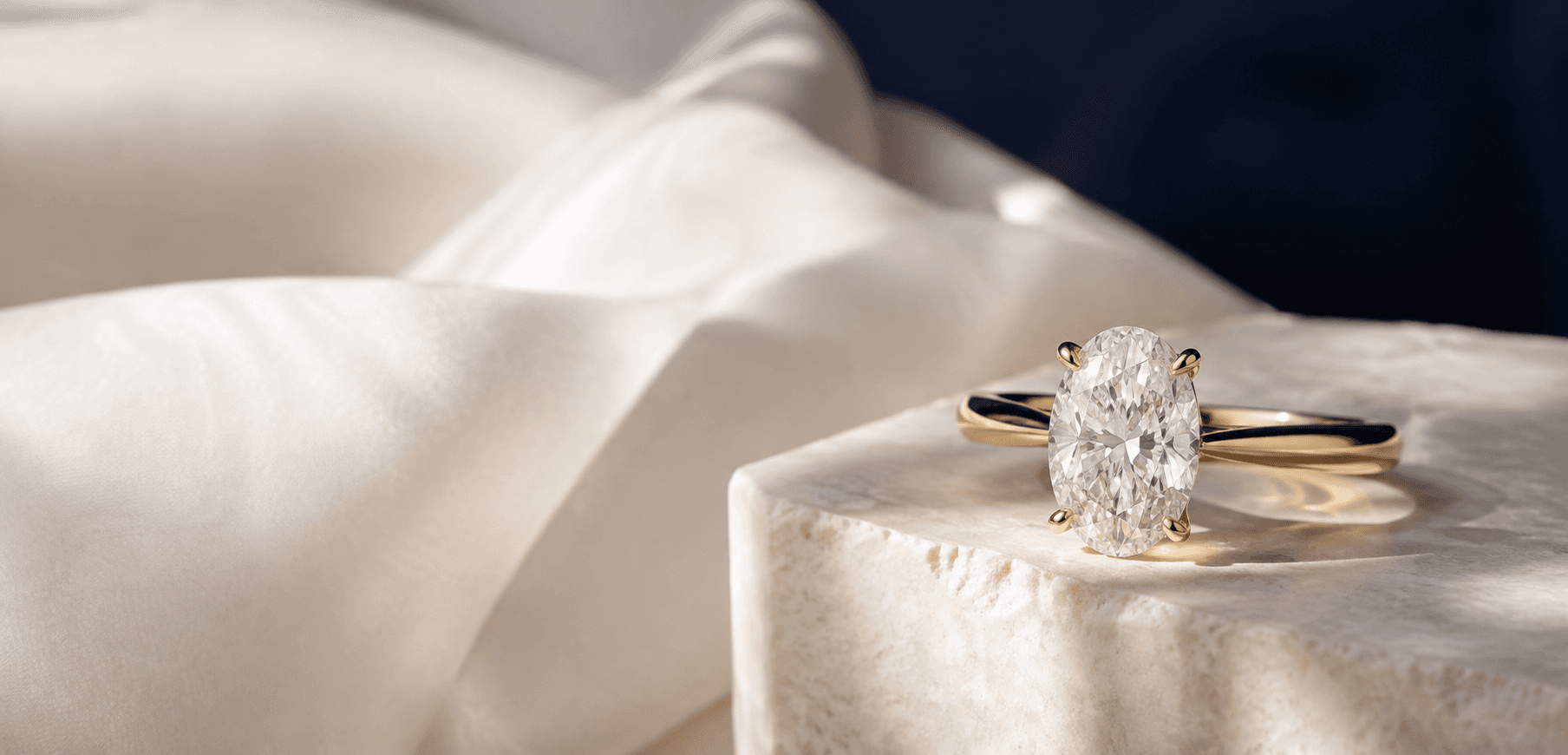 Oval diamond engagement ring styled on ivory silk and stone